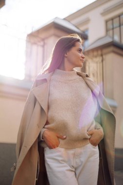 Pelerinli genç bir kadın binanın arka planında caddede yürüyor. Yakın çekim..