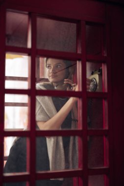 Camdan ankesörlü telefondan arayan genç bir kadına bakın. Yakın çekim..