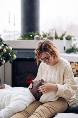 Mutlu ırklar arası çift oturur ve Noel ağacı ve dekorasyonla eğlenir. Irklar arası aile kavramı ve farklı insan ırkları arasındaki birlik.