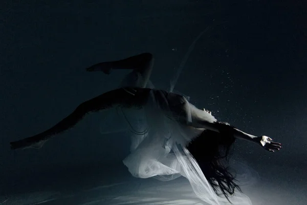 白い飛行中の美しい女性の水中撮影透明なドレスの水の中で日光浴で踊る 光の光線で水面を背景に幻想的な人魚 — ストック写真