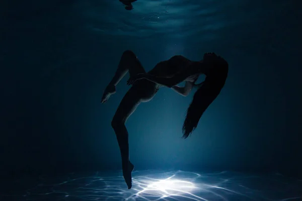 日差しの中で水の中で長い髪のダンスと美しい女性の水中撮影 光の光線で水面を背景に幻想的な人魚 — ストック写真
