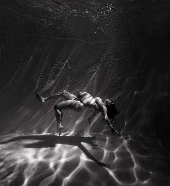 美しい妊婦の水中撮影水の中で日光浴を介して泳ぐ 光の光線と水の背景にファンタジー人魚 白黒の画像 — ストック写真