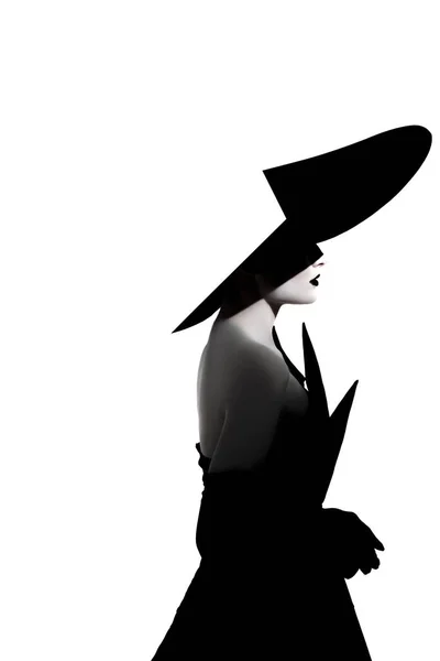 白い背景を背景に スタイリッシュでつばの広い帽子 黒いドレス 手袋をしたスタジオで化粧をした若い女性がポーズをとっている 孤立したイメージ サイドビュー — ストック写真