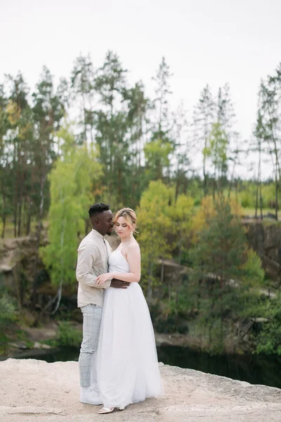Feliz Pareja Interracial Recién Casados Encuentra Roca Abraza Contra Fondo —  Fotos de Stock