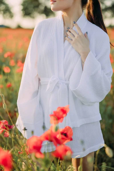 日落时分 身穿白衣的女人在盛开的罂粟丛中漫步 — 图库照片