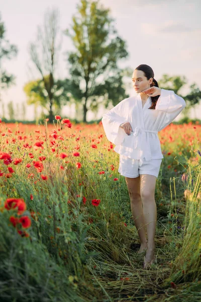 흰옷을 여자가해 꽃피는 양귀비 밭에서 즐긴다 — 스톡 사진