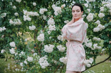 Kimono elbiseli genç esmer kadın çiçeklenen beyaz buzdağının bahçesinde gülerek eğleniyor..