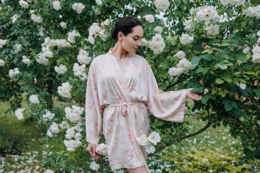 Kimono elbiseli genç esmer kadın çiçeklenen beyaz buzdağının bahçesinde gülerek eğleniyor..