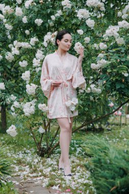 Kimono elbiseli genç esmer kadın çiçeklenen beyaz buzdağının bahçesinde gülerek eğleniyor..