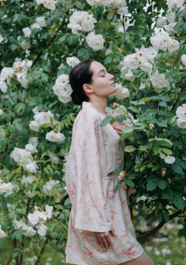 Kimono elbiseli genç esmer kadın bahçedeki beyaz buzdağına tırmanarak gözleri kapalı eğleniyor..