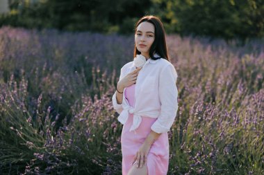 Genç esmer kadın çiçek açan lavantanın arasında yürüyor ve eğleniyor..