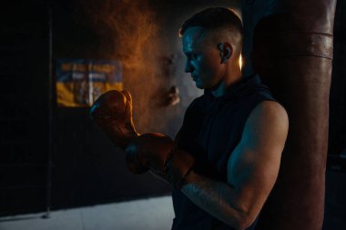Spor salonunda Ukrayna bayrağına karşı egzersiz yaptıktan sonra yüzünde ter damlalarıyla erkek boksörün portresi. Arkaplan.