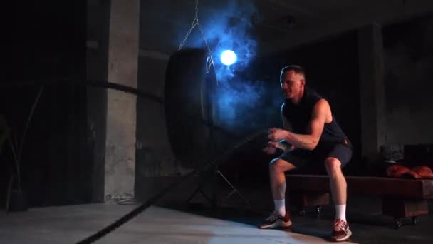 Hombre Musculoso Fuerte Ejercitándose Gimnasio Oscuro Con Cuerdas Combate Cuerdas — Vídeos de Stock