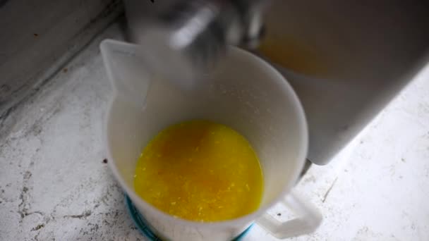 食品厂的工人打开水龙头 一股奶油倒入装有新鲜榨橙汁的桶中 靠近点准备冰淇淋的配料 手工制作的冰淇淋 — 图库视频影像