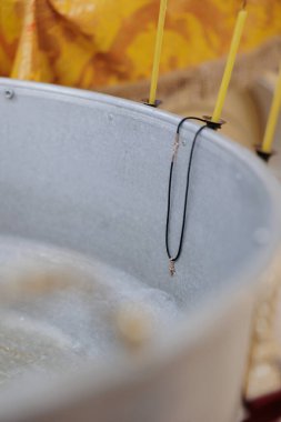 Kutsanmış su, pektoral haç ve mum ile vaftiz fontu. Ortodoks kilisesinde yenidoğanların vaftiz ayini. Yakın çekim..