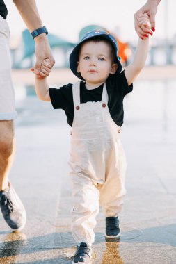 Küçük çocuğun şehirde yürürken ailesinin elini tutarken su birikintisindeki yansımasına yakın plan görüntüsü..