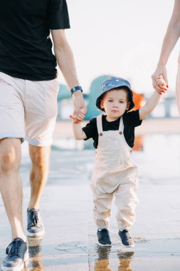 Küçük çocuğun şehirde yürürken ailesinin elini tutarken su birikintisindeki yansımasına yakın plan görüntüsü..