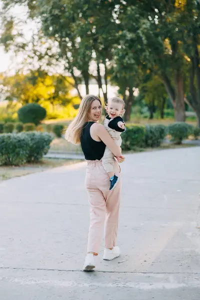 快乐的年轻妈妈在公园里散步的时候很开心 跑着跑着 和她的小孩一起回头看 — 图库照片