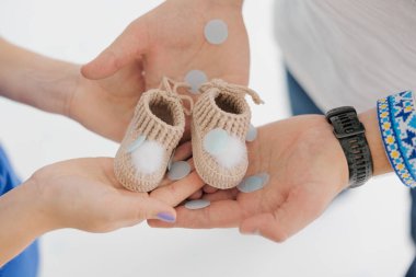 Müstakbel anne babalar yeni doğan bebek için patik tutuyorlar. Aile bir bebeğin doğmasını bekliyor. Ukrayna işlemeli gömlek. Yakın çekim..