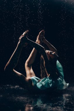 Yeşil elbiseli balerin kız, arka planda düşen su damlalarına karşı dans ediyor. Zarif, güzel balerin. Bale sanatı, zarafet, esneklik, hareket.