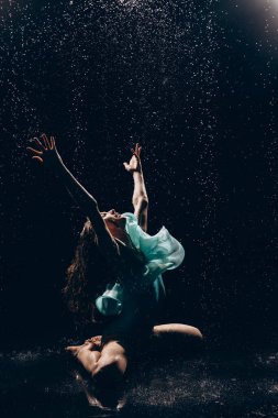 Yeşil elbiseli balerin kız, arka planda düşen su damlalarına karşı dans ediyor. Zarif, güzel balerin. Bale sanatı, zarafet, esneklik, hareket.