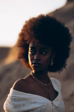 Gün batımında dışarıda poz veren güzel bir Afrikalı kadının portresi. Arka ışıklandırmalı resim.