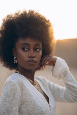 Gün batımında dışarıda poz veren güzel bir Afrikalı kadının portresi. Arka ışıklandırmalı resim.