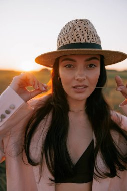 Gün batımında çayırda hasır şapkalı güzel bir kadının portresi. Arkaplan.