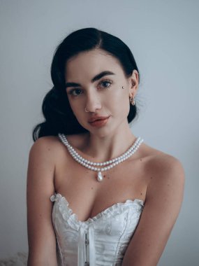 İnci kolyeli seksi esmer kadın portresi ve dantelli erotik saten beden. Vücut şekillendirici korse. Düğün için erotik iç çamaşırı..