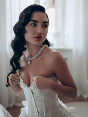 Yatak odasında dantelli, erotik, saten bir elbise giymiş seksi bir kadın. Vücut şekillendirici korse, sıkılaştırıcı korse. Düğün için erotik gelinlik. Yakın plan..