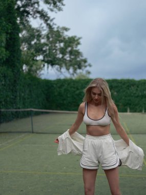 Spor giyim sektöründe genç bir bayan tenis antrenmanından sonra açık alanda internetin arka planına karşı dinleniyor. Yakın plan..