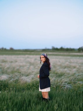 Genç bir kadın, bozkırda, mavi gökyüzü olan güzel manzaraya karşı tüy otlarının arasında duruyor ve dinleniyor. Ukrayna 'da bozkır çimenli yaz manzarası.