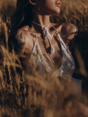 Beyaz sütyenli genç, güneşli kadın olgunlaşmış buğday başaklarının arasında tarlada rahatlıyor. Huzurlu kırsal yaz manzarası, doğal güzellik. Yakın plan. Vücut parçası.