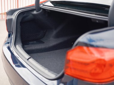 Bagajı açık, geniş, boş kargo alanı ve parlak arka lambaları olan modern koyu renkli bir sedan. Seyahat, depolama ve otomotiv işlevselliği temaları için ideal.