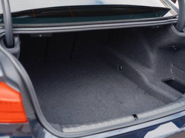 Bagajı açık, geniş, boş kargo alanı ve parlak arka lambaları olan modern koyu renkli bir sedan. Seyahat, depolama ve otomotiv işlevselliği temaları için ideal.