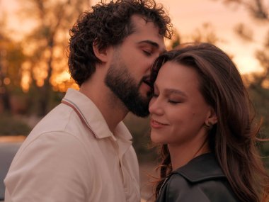 Sevgi dolu bir çift gün batımında dışarıda birlikte romantik bir anın tadını çıkarıyor, samimi fısıltılar ve tatlı gülücükler paylaşıyorlar..