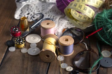 Renkli iplikler ve dikiş için ögeler, eski bir arkaplanda.