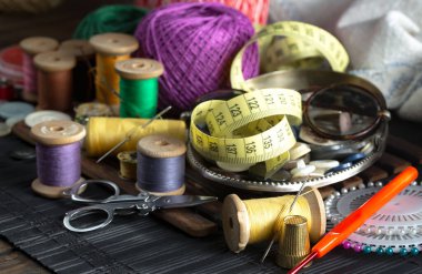 Renkli iplikler ve dikiş için ögeler, eski bir arkaplanda.