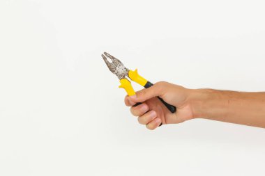 Tamircinin eli kesme yolları olan beyaz arkaplanda izole edilmiş bir kerpeten tutuyor.