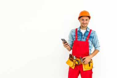 meslek, inşaat ve bina - mutlu gülümseyen erkek işçi veya miğfer ve genel olarak akıllı telefon beyaz arka plan üzerinde inşaatçı.