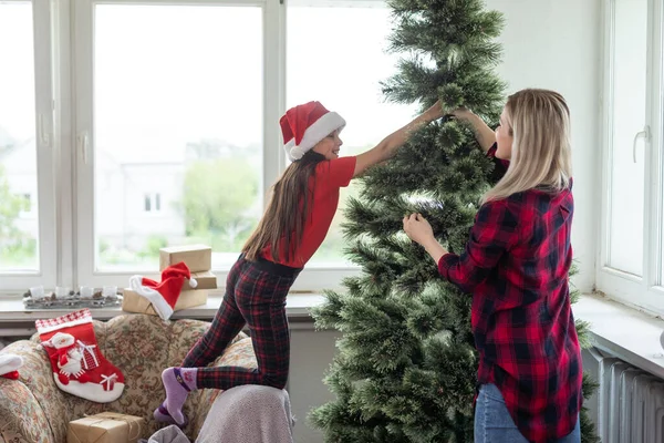 家族や冬の休日や人々のコンセプト 家でクリスマスツリーを飾る幸せな母親と小さな娘 — ストック写真