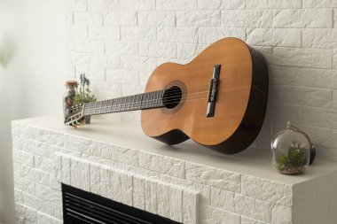 Minimalist iç tasarım konsepti. Gri tekstil koltukta akustik gitar. Dairenin geniş odasındaki ahşap desenli lamine döşeme. Arkaplan, kopyala boşluk, kapat.