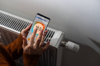 Kişi el ayarı Mobilephone evde kullanma termostat sıcaklığını Close-Up.