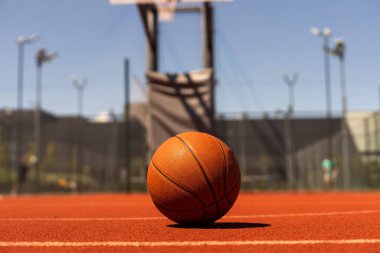 Top view orange ball for basketball lying on the rubber sport court. Sport red ground outdoor in the yard.