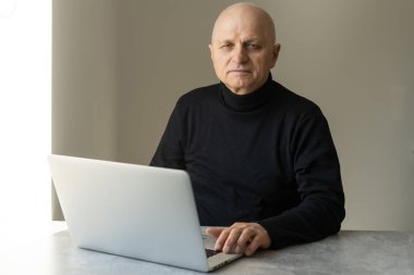 Şık giyinmiş yakışıklı yaşlı adam dizüstü bilgisayar kullanıyor..