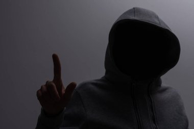 Kapüşonlu bir adamın stüdyo portresi, bir gölge yüzünü gizliyor. Anonimlik gölge ekonomi ve kanundan kaçma.