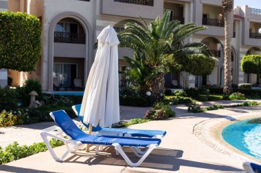 Temiz suyu olan bir yüzme havuzu, hiç kimse. Kare şeklinde bir havuz, mavi fayanslar, çekmeceler ve güvertelerde güneşlik, insan yok. Su yüzeyi. Genel bakış. Yaz arkaplanı