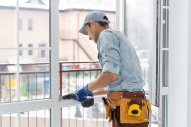 Yükleme penceresi içinde ev inşaat işçisi. Tornavida ile pencereyi tamir tamirci.