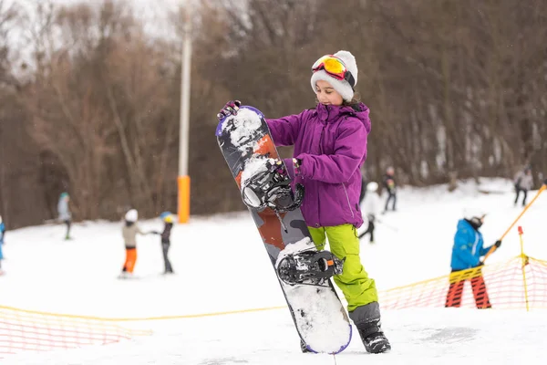 スノーボードウィンタースポーツ 暖かい冬の服を着て雪と遊ぶ小さな子供の女の子 冬の背景 — ストック写真