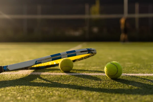 stock image tennis balls and racket on the green grass background.